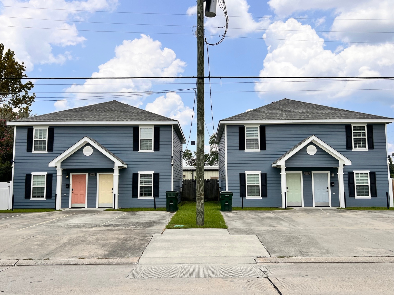 The two blue duplex buildings at Lake Charles Vacation Rentals, with four colorful front doors
